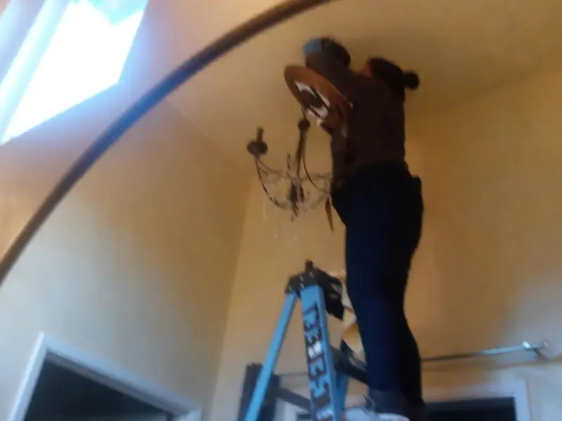 Electrician installing a chandelier in a Hudson residence
